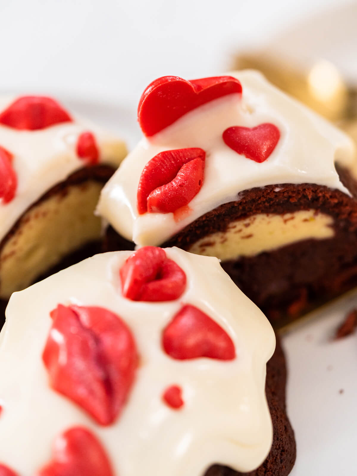 Angeschnittene Kuchenstücke mit weißer Glasur und dreidimensionalen roten Herzen und Lippen