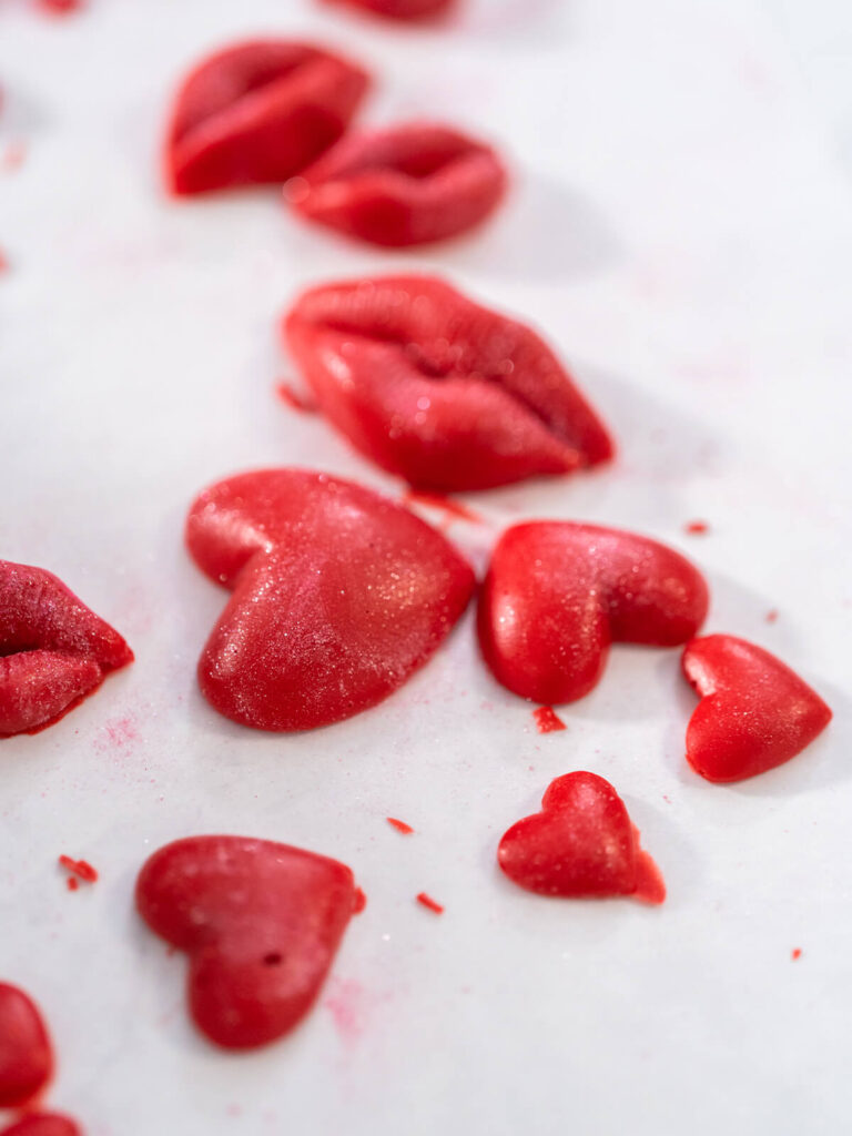 Rote Schoko-Herzen und Schoko-Lippen mit Perlmuttschimmer nach dem Auftragen von Glanzpuder