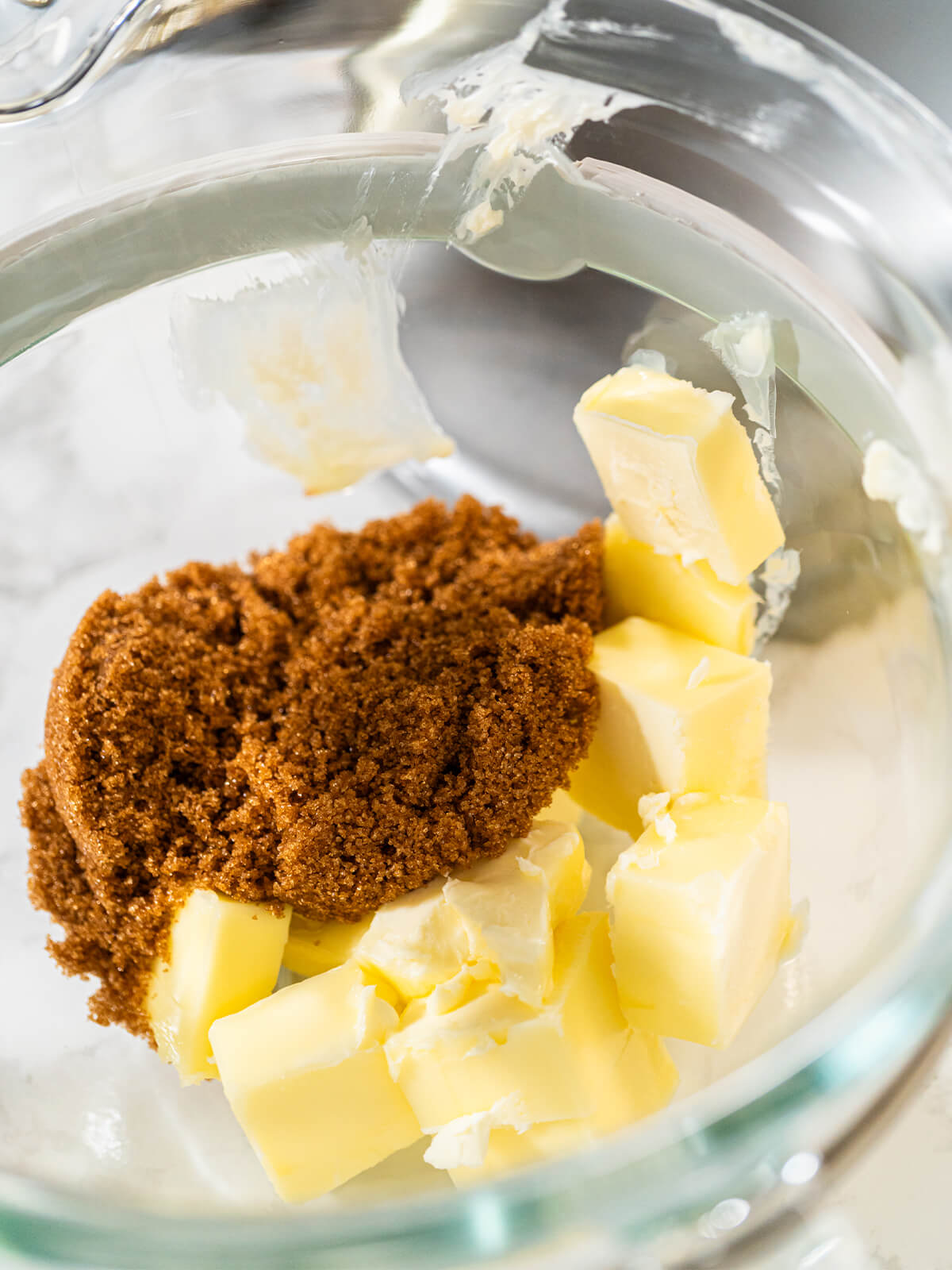 Gewürfelte Butter und ein Haufen brauner Zucker in einer Glasschüssel