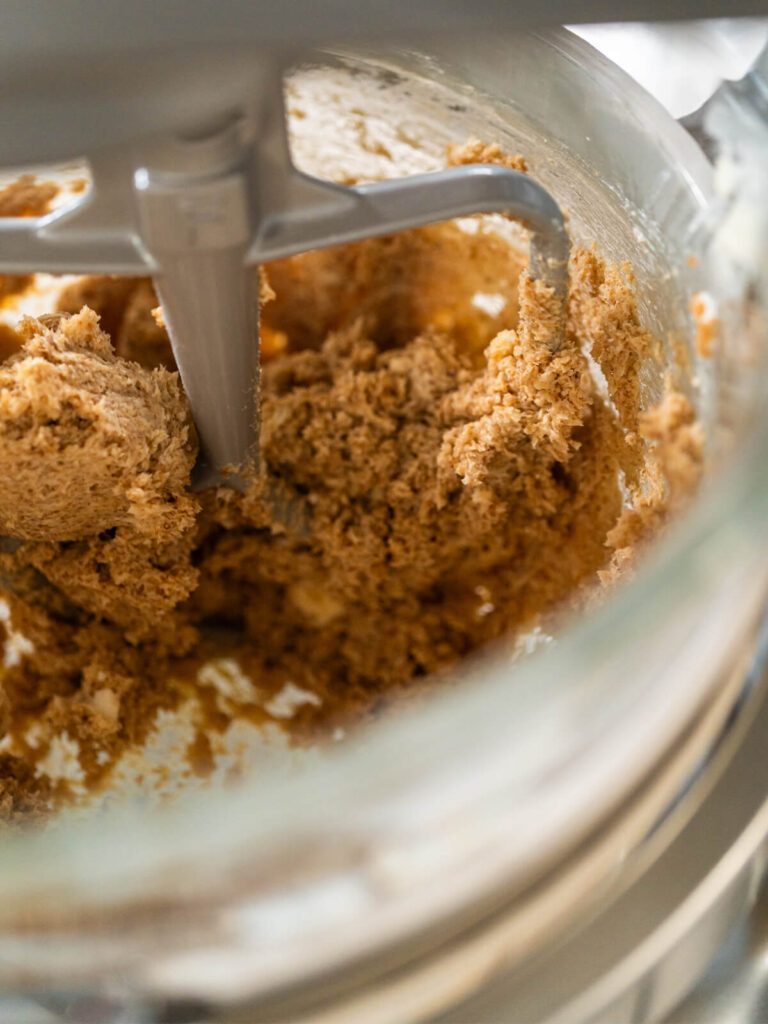 Hell und cremig aufgeschlagene Butter-Zucker-Masse mit dunklen Gewürzpunkten in der Küchenmaschine
