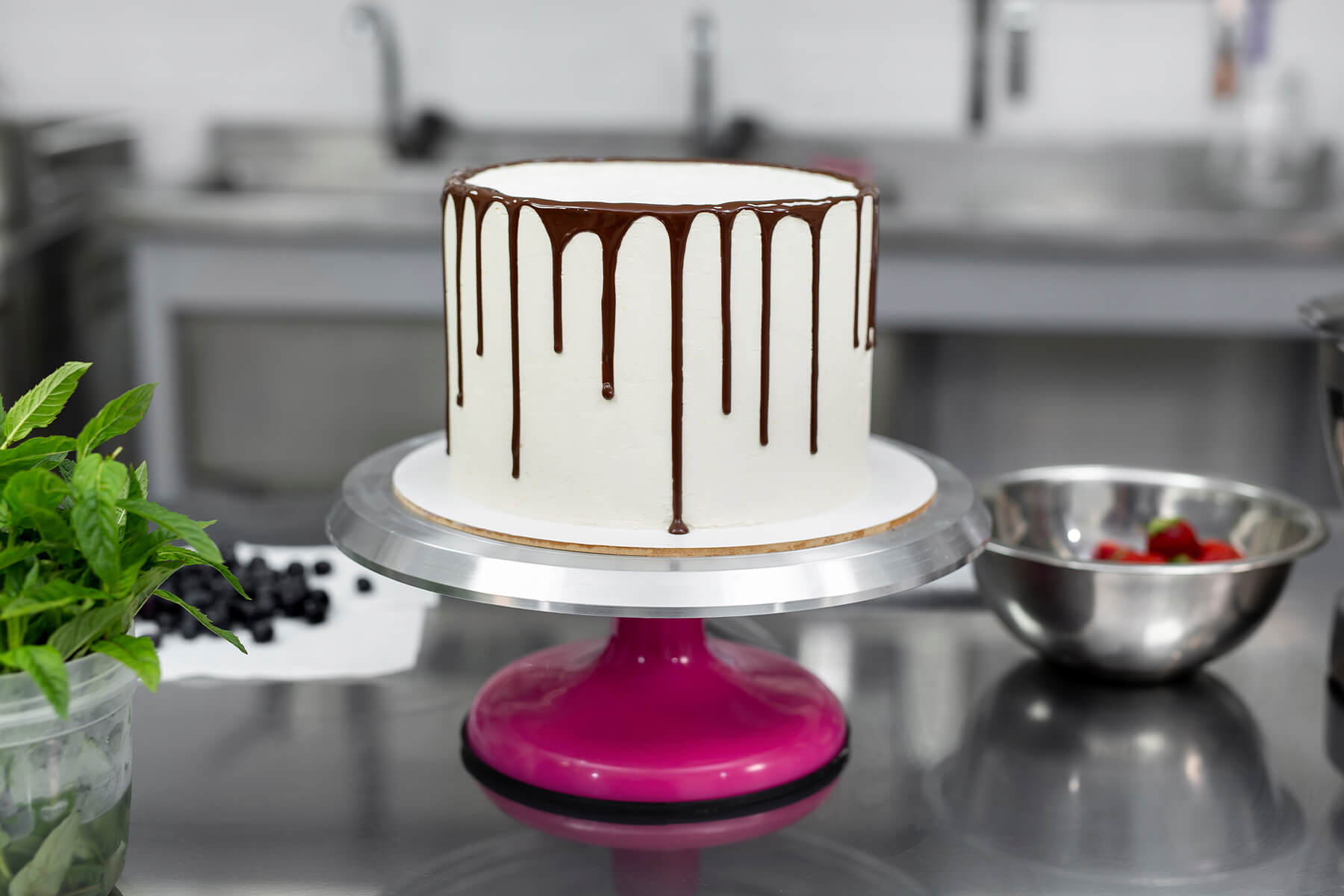 Fertiger Schokoladen-Drip auf einer hohen weißen Torte vor der Dekoration, die Nasen enden auf unterschiedlichen Höhen