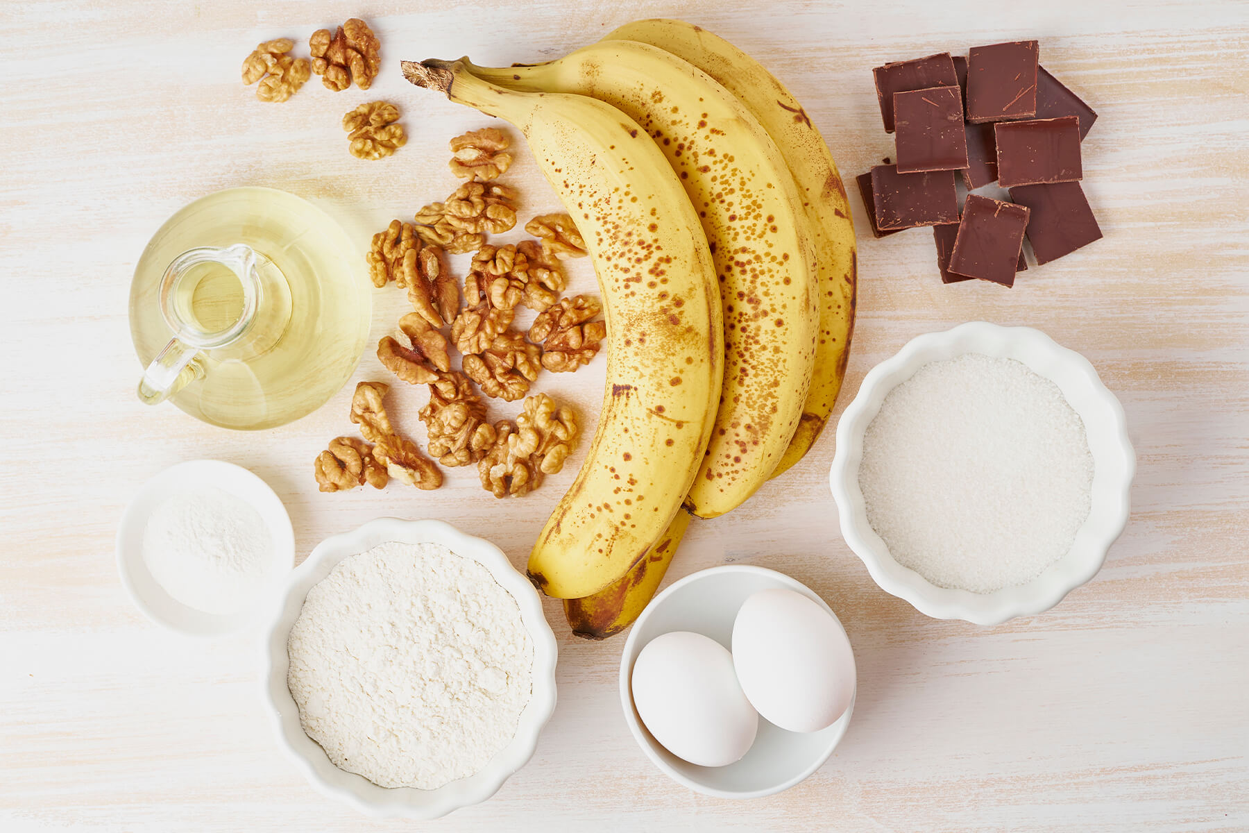 Zutaten für Bananenbrot mit Walnüssen und Schokolade - reife Bananen, Walnusskerne, Zartbitterschokolade, Mehl, Zucker, Eier, Öl und Backpulver