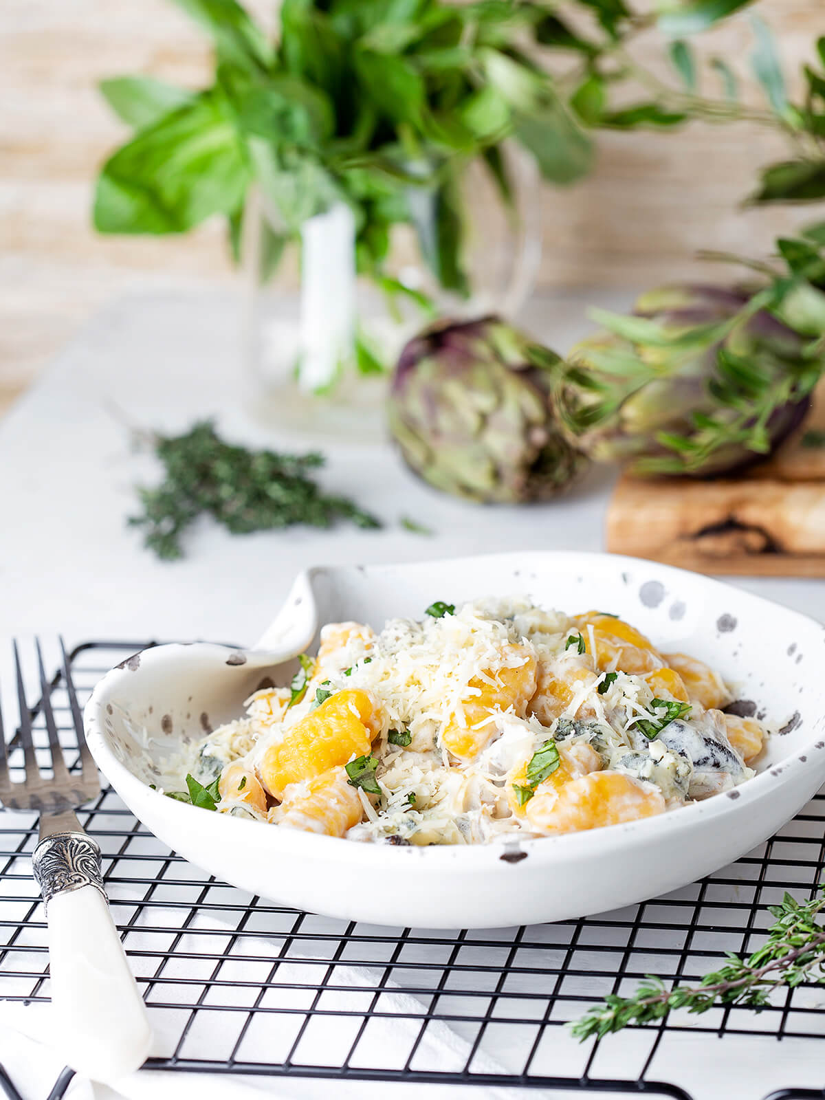 Schale mit Kürbisgnocchi, Steinpilzen, Gorgonzolasauce und Parmesan, daneben Artischocken und Thymian