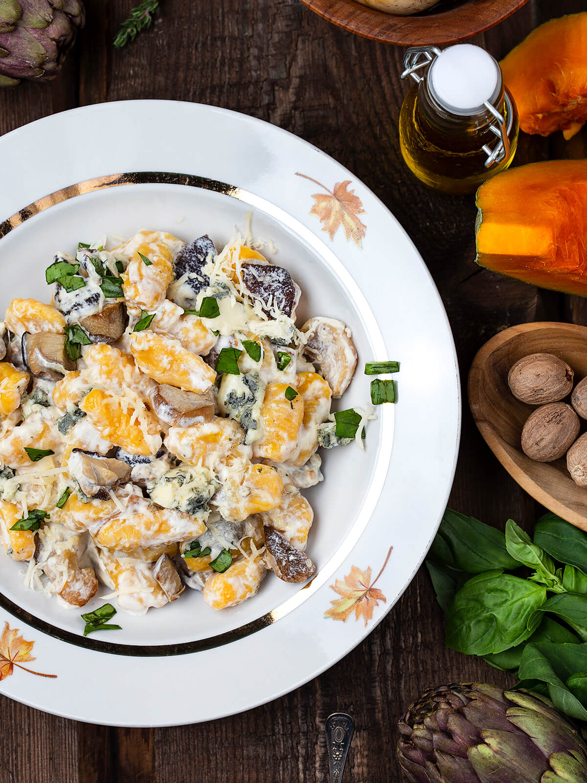 Kürbisgnocchi in heller Sauce mit Steinpilzen, Blauschimmelkäse und Basilikum in einer Schale