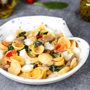 Schale mit Orecchiette, gebratenen Champignons, Spinat, Kirschtomaten und Mozzarellastücken