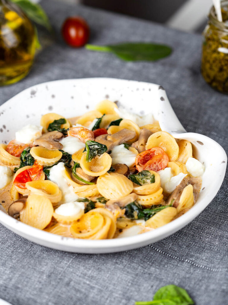 Schale mit Orecchiette, gebratenen Champignons, Spinat, Kirschtomaten und Mozzarellastücken