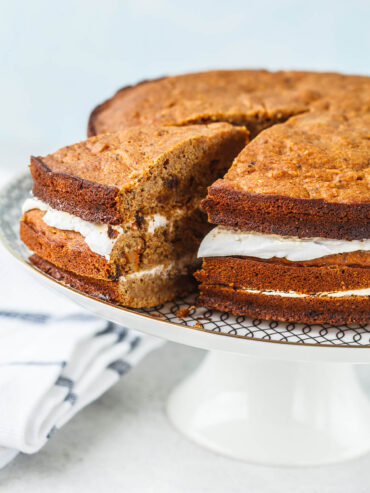 Angeschnittener veganer Karottenkuchen aus drei Böden mit zwei Schichten Kokoscreme