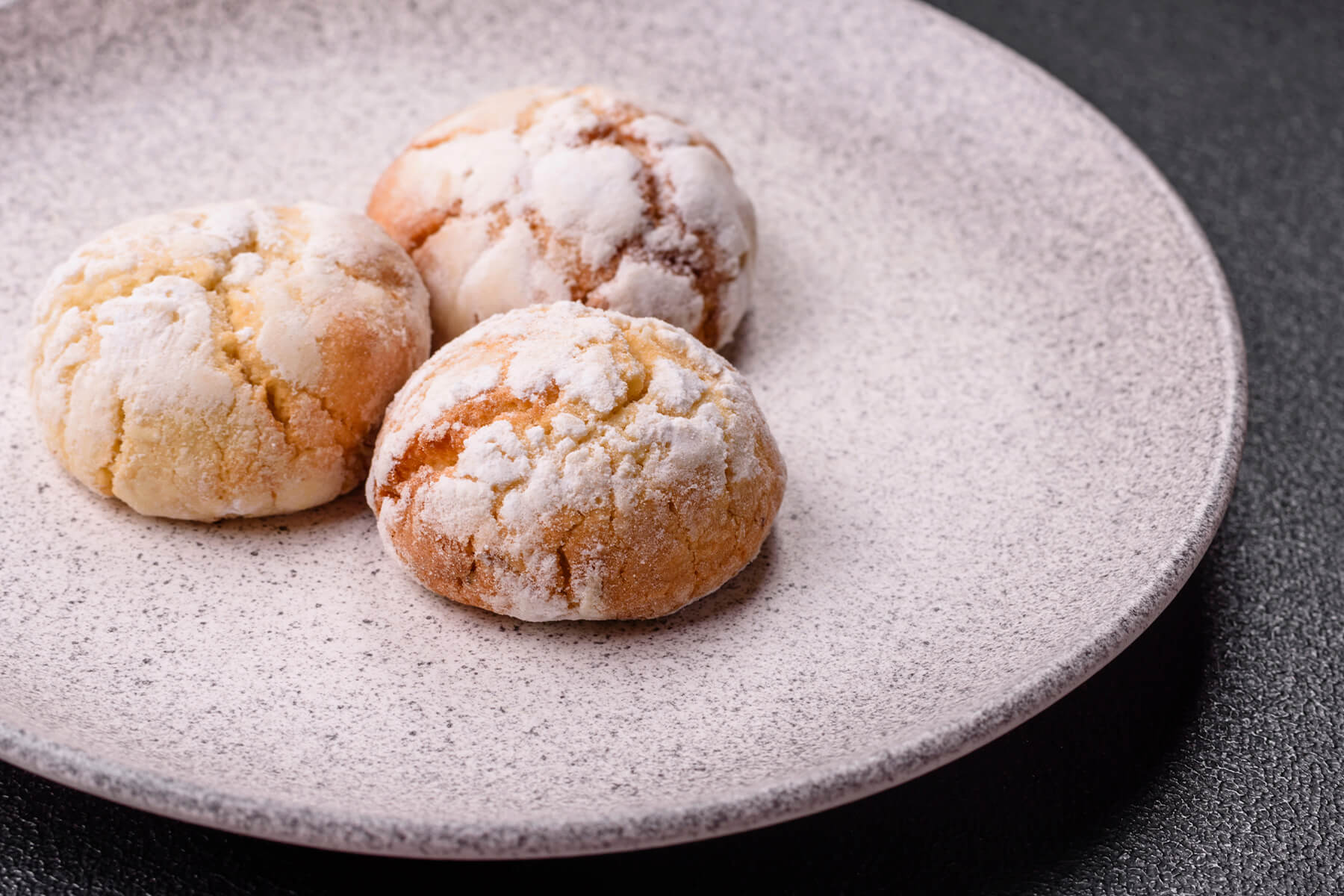 Drei weiche Amaretti Morbidi mit dicker Puderzuckerschicht und aufgesprungenen Rissen von oben