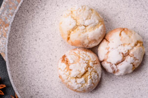 Weiche Amaretti Morbidi mit Puderzucker auf einem hellen gesprenkelten Teller