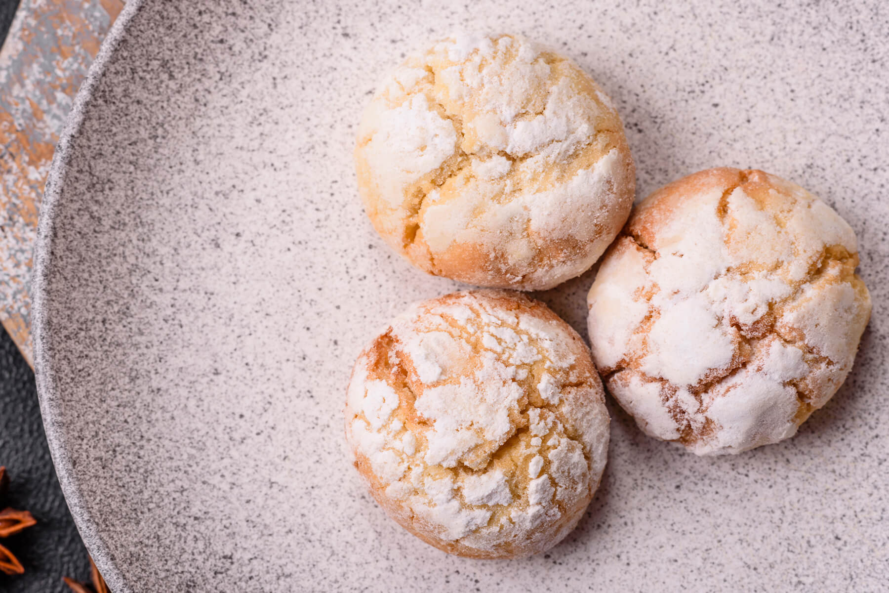 Weiche Amaretti Morbidi mit Puderzucker auf einem hellen gesprenkelten Teller