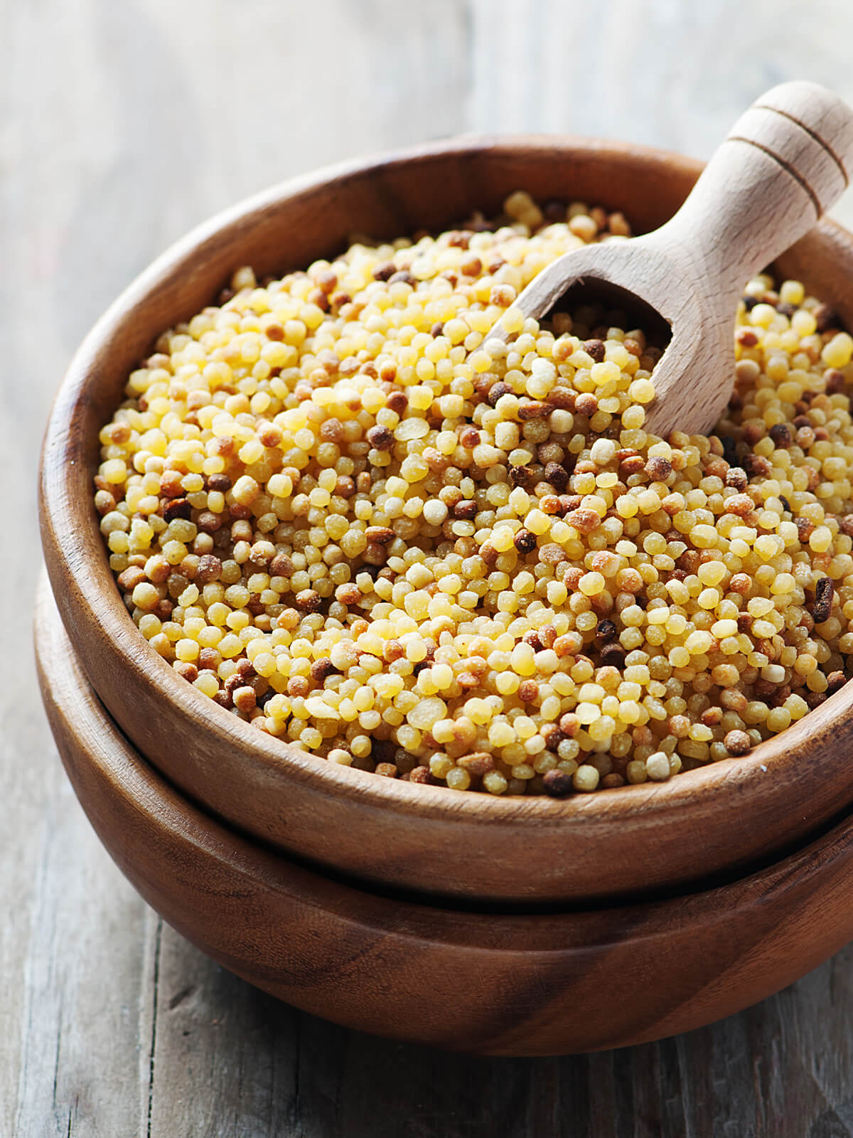 Getrocknete Fregola sarda in einer Holzschale, Körner in ungleichen Größen mit gerösteten Stellen