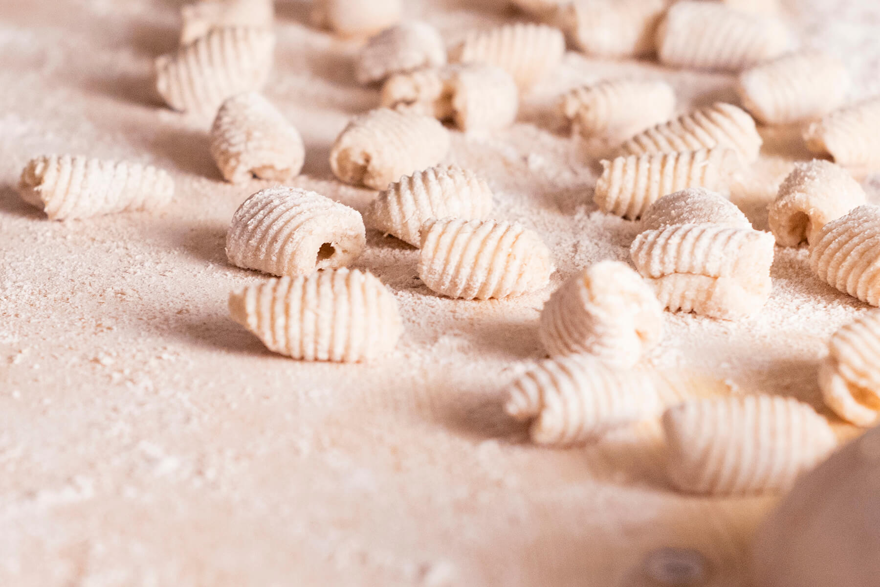Fertig geformte Gnocchi mit deutlichen Rillen und offener Höhlung auf bemehlter Fläche