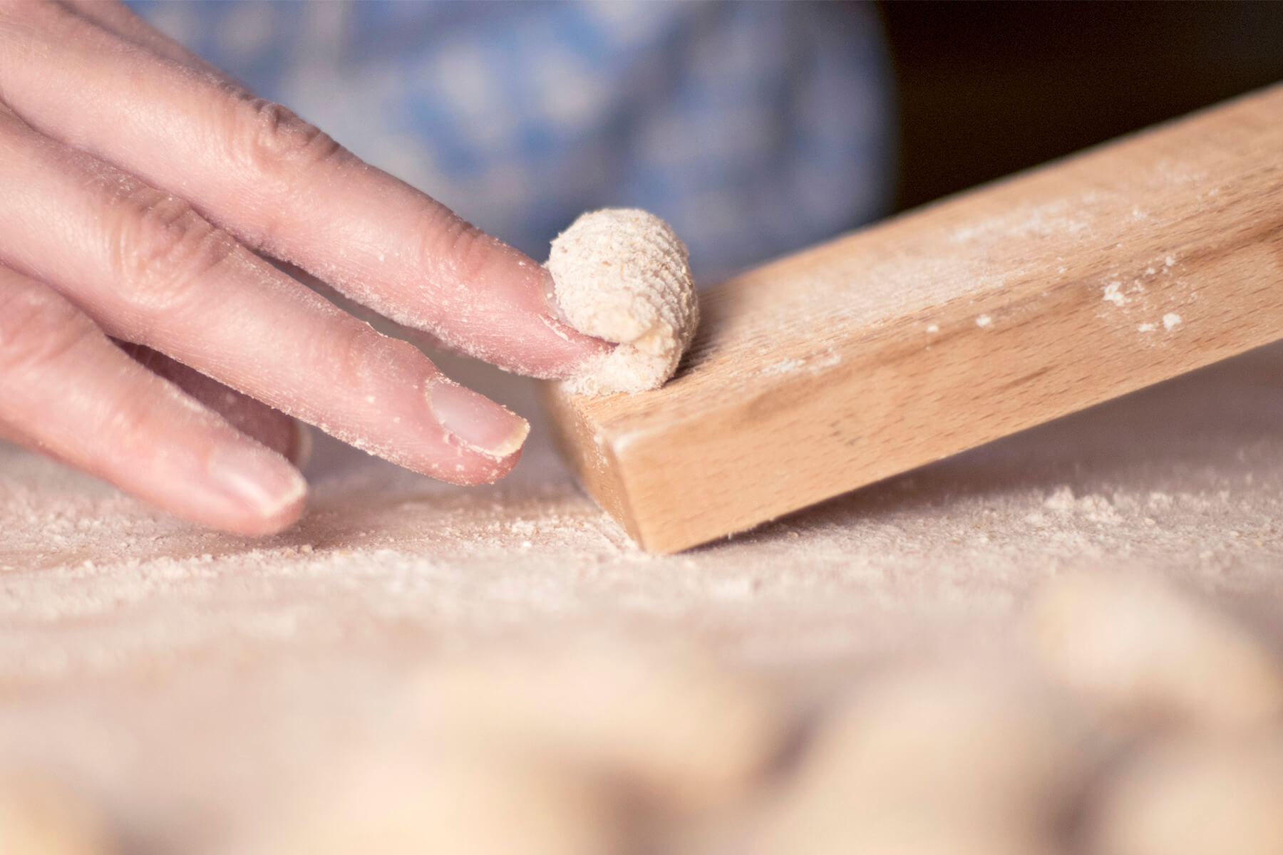 Fingerkuppen setzen ein kleines Teigstück quer an die obere Kante eines Gnocchi-Bretts an