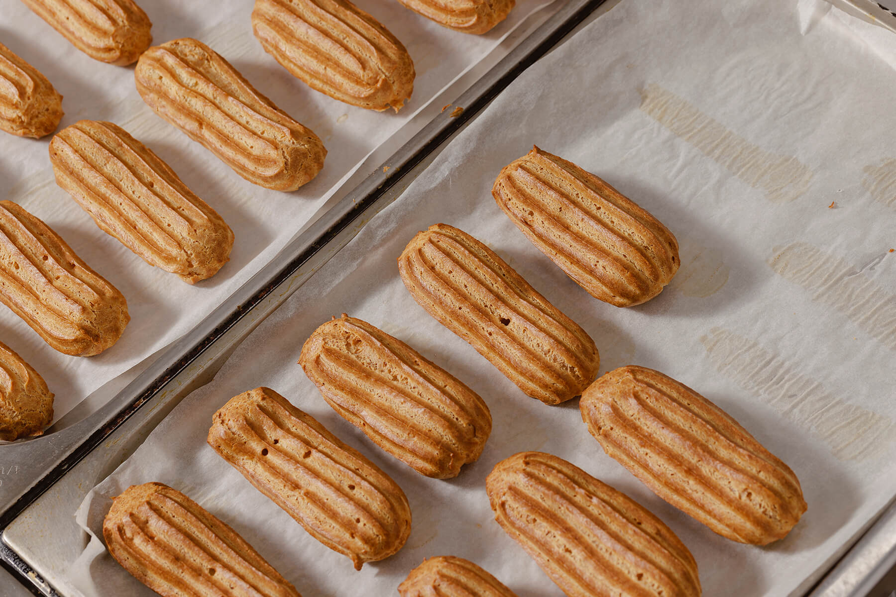 Nahaufnahme goldbraun gebackener Éclair-Hüllen mit deutlichem Rillenrelief