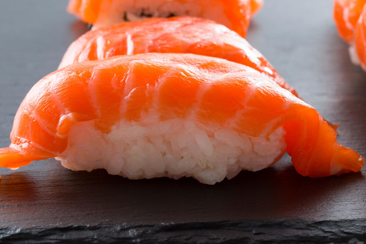 Nigiri mit Lachs auf einer dunklen Schieferplatte