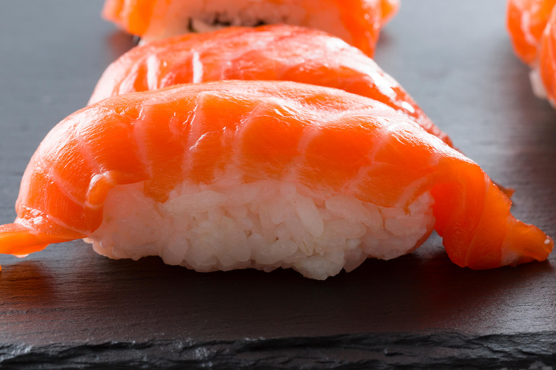 Nigiri mit Lachs auf einer dunklen Schieferplatte